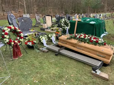 Sarg steht auf Grablegungsvorrichtung auf Rasenfläche, bereit für traditionelle Erdbestattung